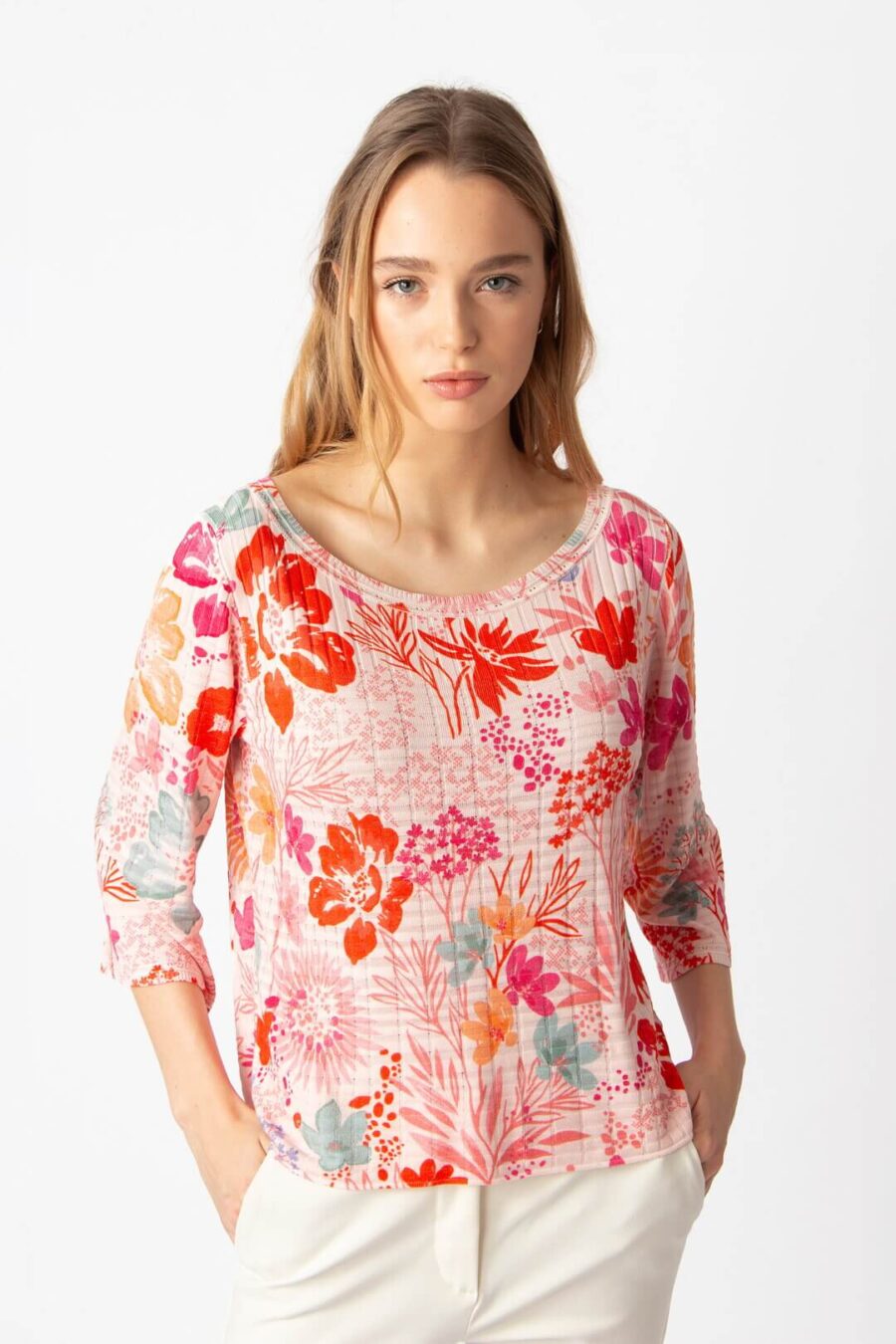 Model draagt IVKO pullover met bloemendessin in koraaltinten, boothals en driekwartmouwen, vooraanzicht.