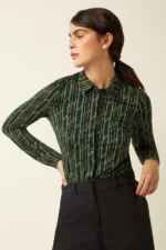 Model draagt King Louie Blouse Brina in retro groen motief, voorkant zichtbaar