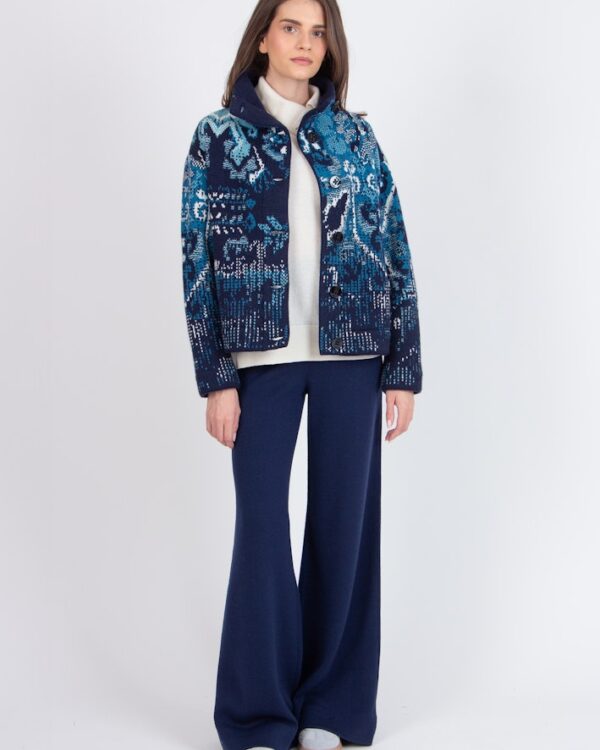 Model draagt een blauw Ivko vest met kilim motief, open gedragen over een witte coltrui en gecombineerd met donkerblauwe wijde broek.