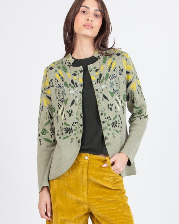 Model draagt een groen Ivko vest van 100% katoen met Plantopia botanische print, gecombineerd met mosterdgele corduroy broek.